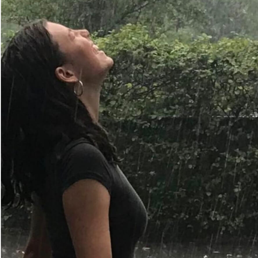 Ellie steht lachend im Regen und schaut nach oben