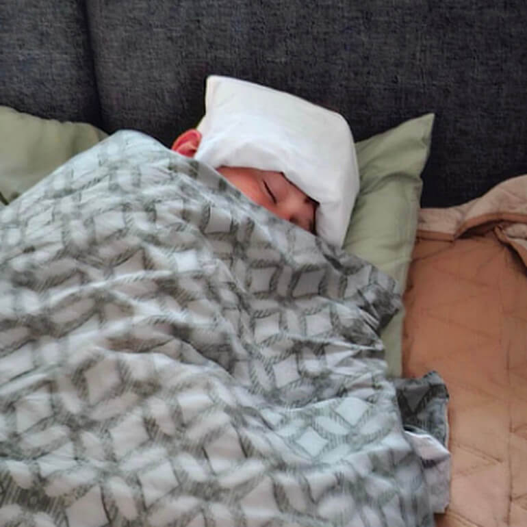 Fritz liegt im Bett, die Bettdeck ganz hochgezogen, auf der Stirn ein Kühlpad