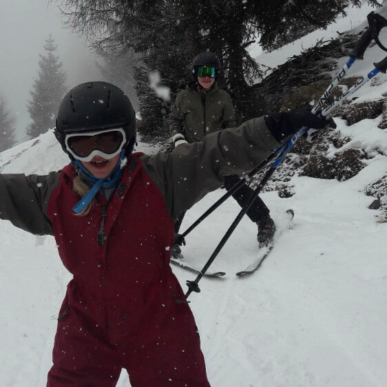 Greta vor der Diagnose ME/CFS. Sie steht lächelnd in Ski-Ausrüstung im Schnee