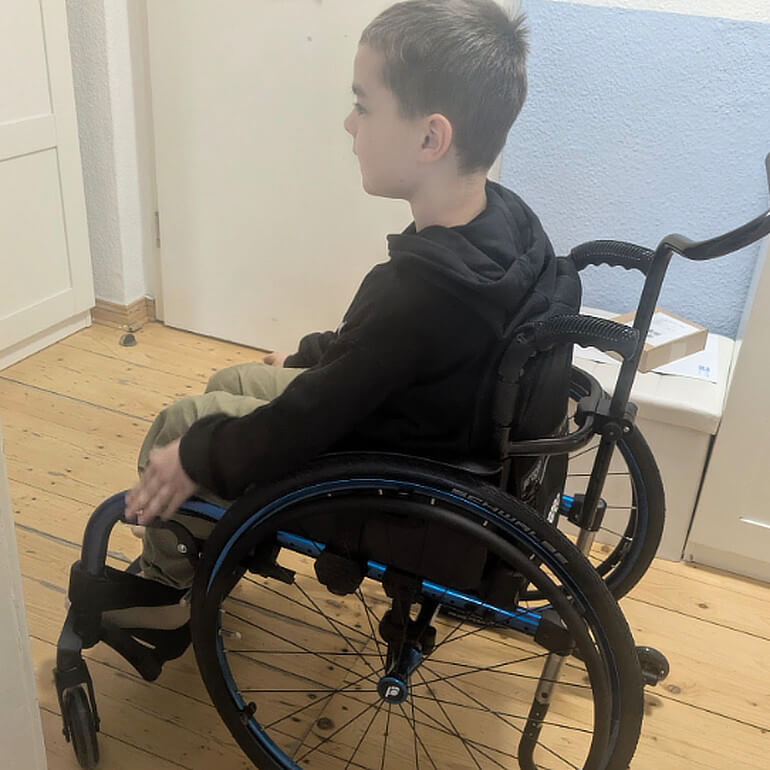 Max sitzt in der Wohnung im Rollstuhl