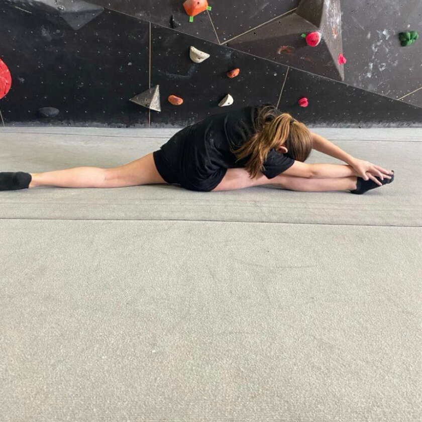 Melina macht Spagat vor einer Kletterwand