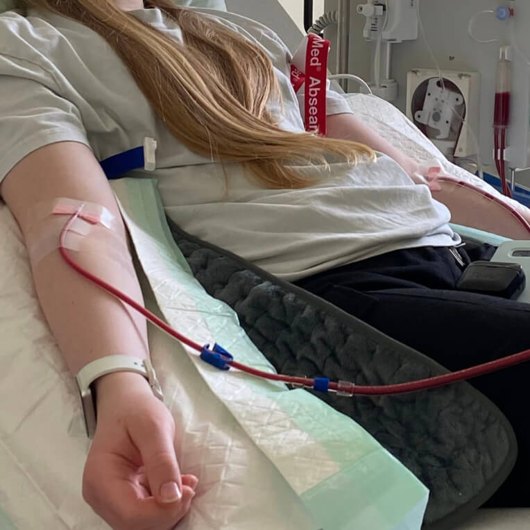Mia mit ME/CFS im Krankenhausbett an einen Tropf angeschlossen