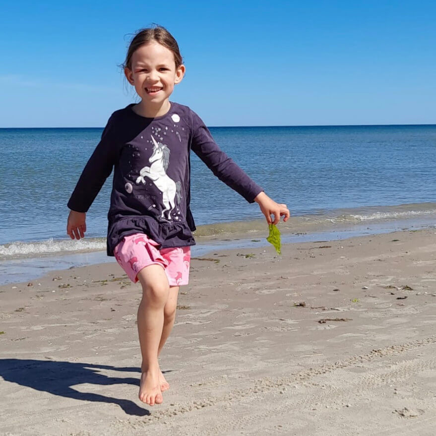 Nele vor der Diagnose ME/CFS. Sie läuft lächelnd über den Strand, im Hintergrund das Meer