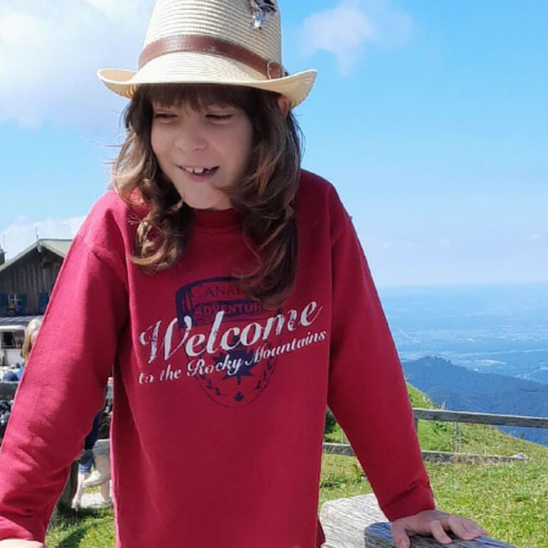 Tim auf einem Berggipfel, im Hintergrund die Tal-Landschaft